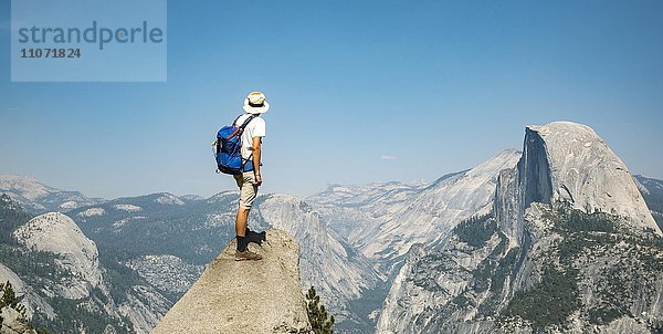 Junger Mann steht auf Felsvorsprung und blickt auf den Half Dome  Ausblick vom Glacier Point  Yosemite Nationalpark  Kalifornien  USA  Nordamerika