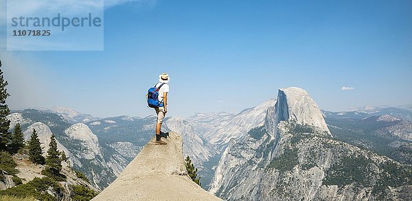 Junger Mann steht auf Felsvorsprung und blickt auf den Half Dome  Ausblick vom Glacier Point  Yosemite Nationalpark  Kalifornien  USA  Nordamerika