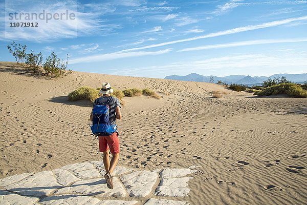 Junger Mann  Tourist wandert auf Sanddünen  Mesquite Flat Sand Dunes  Death Valley  Death-Valley-Nationalpark  Kalifornien  USA  Nordamerika