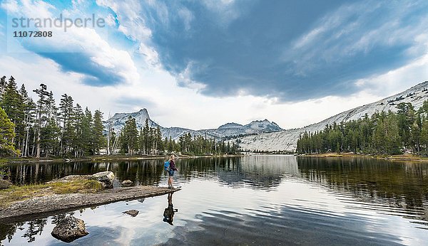 Wanderin steht an einem See  Lower Cathedral Lake  Sierra Nevada  Yosemite Nationalpark  Kalifornien