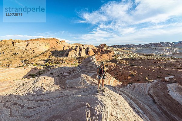 Touristin  Wanderin an der Fire Wave Sandsteinformation  dahinter Felsformation Sleeping Lizard  Valley of Fire State Park  Nevada  USA  Nordamerika