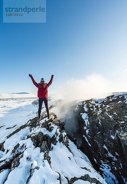 Frau steht an Kontinentalspalte zwischen Nordamerikanischer und Eurasischer Platten  Mittelatlantischer Rücken  Grabenbruch  Krafla  Mývatn  Nordisland  Island  Europa