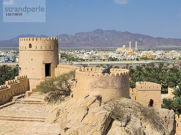 Fort Nakhl  oder Husn Al Heem  Festung  über Oase Nakhl auf Jebel Nakhl Massiv  historischer Lehmbau  hinten Nachl mit der großen Moschee  Provinz Al-Batinah  Sultanat Oman  Golfstatt  Arabische Halbinsel  Naher Osten