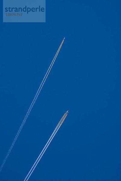 Kondensstreifen von zwei Flugzeugen am blauen Himmel