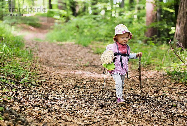 Kleinkind mit Puppe und Spazierstock beim Wandern durch den Wald  Allensbach  Bodensee  Deutschland  Europa