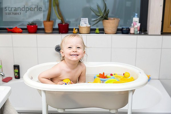 Kleinkind beim Baden in der Kinderbadewanne mit Gummienten
