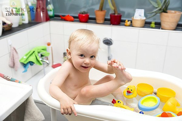 Kleinkind beim Baden in der Kinderbadewanne mit Gummienten