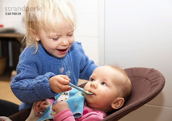 Geschwister  Schwester füttert Baby