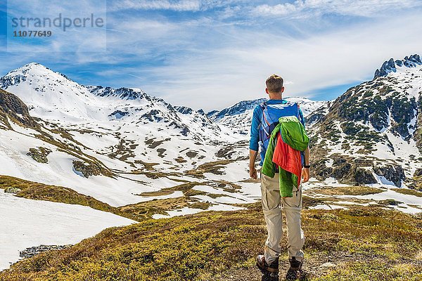 Junger Mann  Wanderer schaut in die Ferne  Berglandschaft mit Schneeresten  Rohrmoos-Untertal  Schladminger Tauern  Schladming  Steiermark  Österreich  Europa