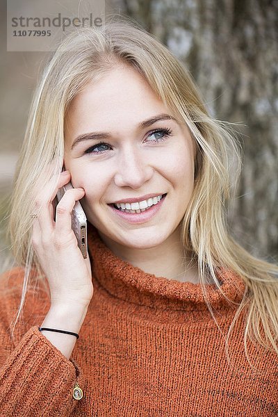 Blondes junge Frau telefoniert mit einem Handy