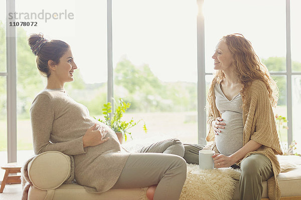 Schwangere Frauen trinken Tee und reden im Wohnzimmer