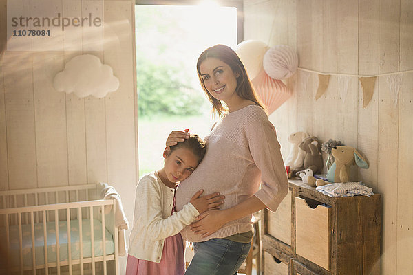 Portrait lächelnde schwangere Mutter und Tochter im Kinderzimmer