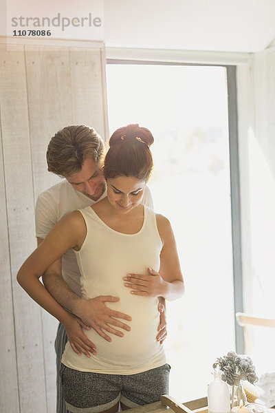 Schwangeres Paar hält Magen in sonnigem Bad