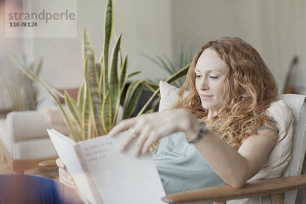 Frau liest Buch im Sessel