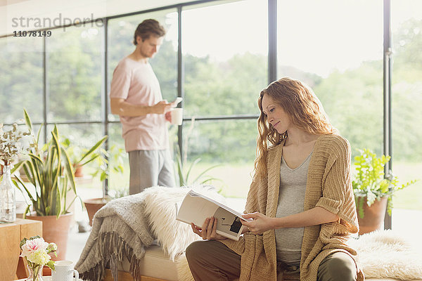 Schwangere liest Buch im Wohnzimmer