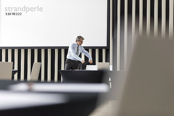 Geschäftsmann platziert Jacke auf Stuhl im Konferenzraum