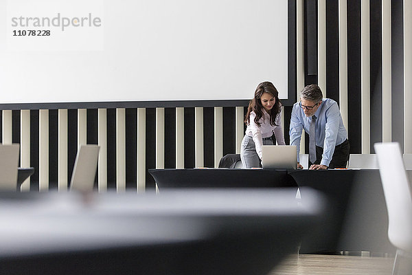 Geschäftsmann und Geschäftsfrau mit Laptop im Konferenzraum