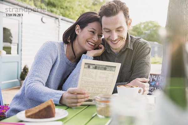 Lächelndes Paar schaut auf die Speisekarte im Outdoor-Café