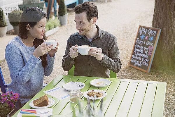 Paar genießt Cappuccinos und Dessert in einem Outdoor-Café
