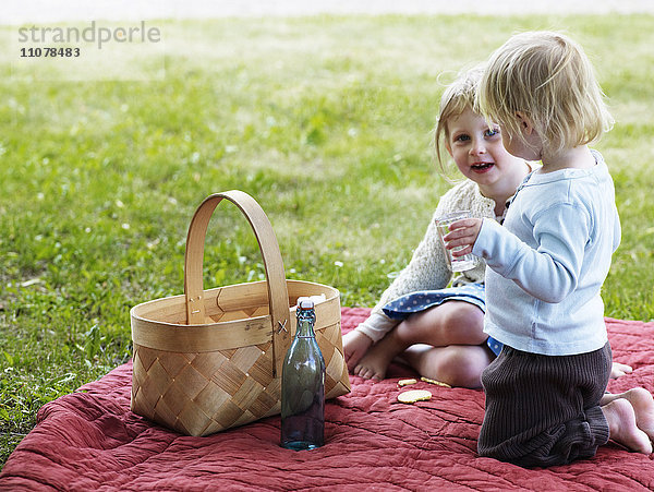 Zwei Mädchen sitzen auf einer Picknickdecke