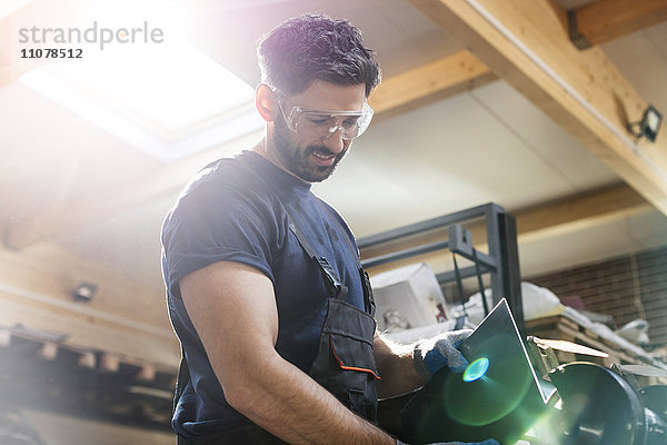 Stahlarbeiter mit Schleifmaschine in der Werkstatt