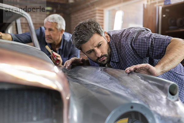 Fokussierter Mechaniker untersucht Oldtimer-Panel in der Kfz-Werkstatt