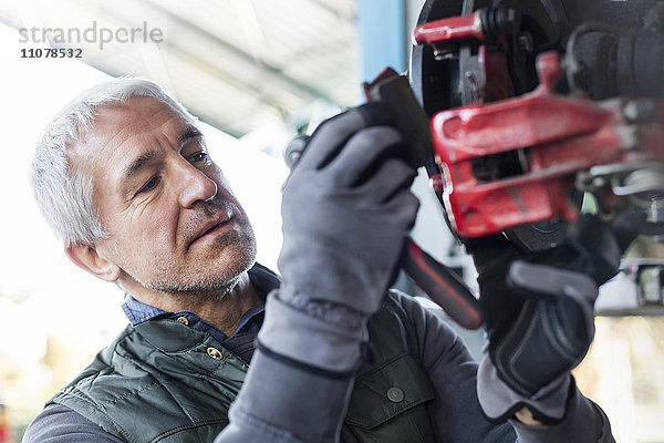 Fokussierter Mechaniker beim Bremsbelagwechsel in der Kfz-Werkstatt