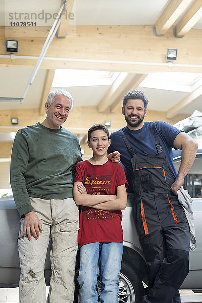 Portraits lächelnde Mehrgenerationen-Mechanikerfamilie in der Kfz-Werkstatt