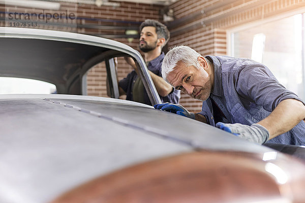 Fokussierter Mechaniker untersucht Oldtimer-Panel in der Kfz-Werkstatt