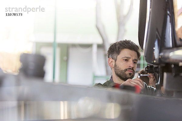 Fokussierte Mechaniker Reparatur Auto in Kfz-Werkstatt