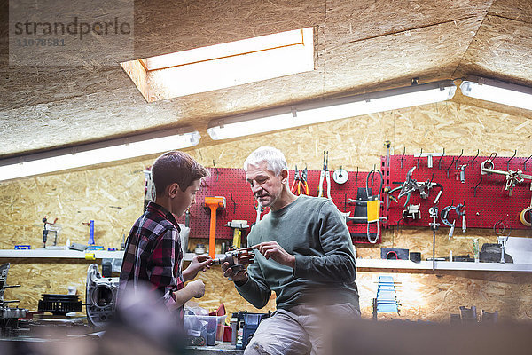 Vater erklärt dem Sohn das Werkzeug in der Autowerkstatt