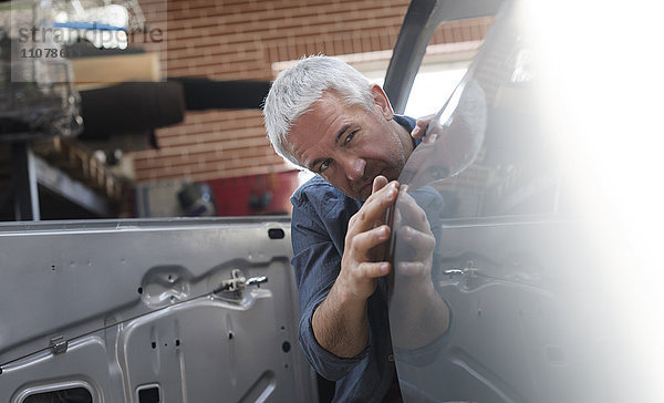 Mechaniker bei der Prüfung der Fahrzeugverkleidung in der Kfz-Werkstatt