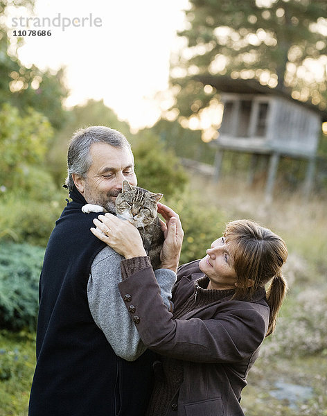Älteres Paar umarmt Katze im Freien