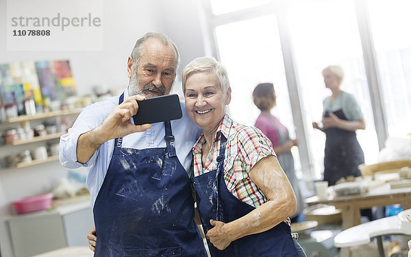 Seniorenpaar nimmt Selfie im Töpferstudio auf