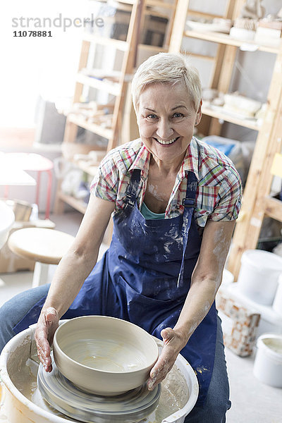 Portrait lächelnde Seniorin mit Töpferscheibe im Atelier
