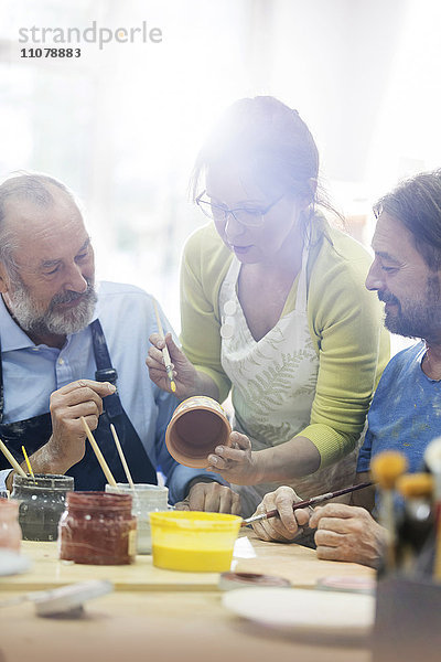 Lehrer leitet reife Männer beim Töpfern im Atelier