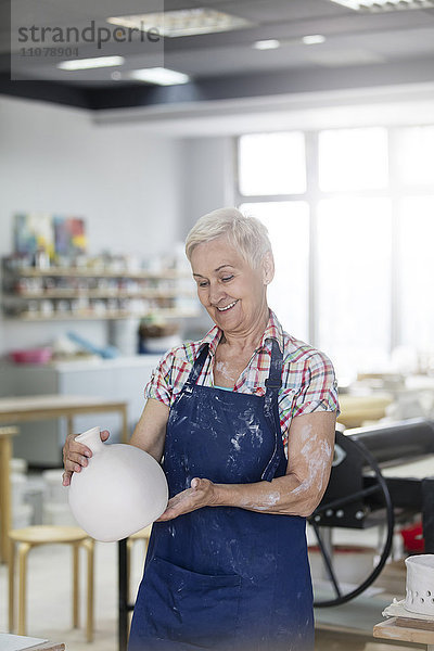 Lächelnde Seniorin mit Keramikvase im Atelier