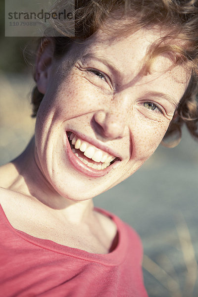 Porträt einer sommersprossigen jungen Frau  die lacht