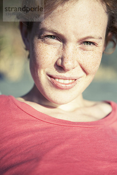 Porträt einer sommersprossigen jungen Frau  die lächelt