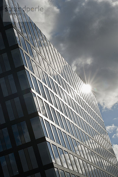 Fassade eines modernen Gebäudes mit von hinten leuchtender Sonne