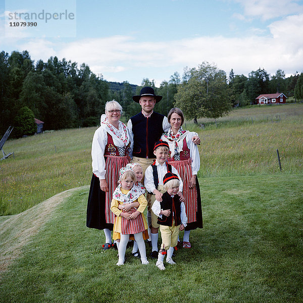 Familie in traditioneller Kleidung auf einer Wiese stehend  lächelnd