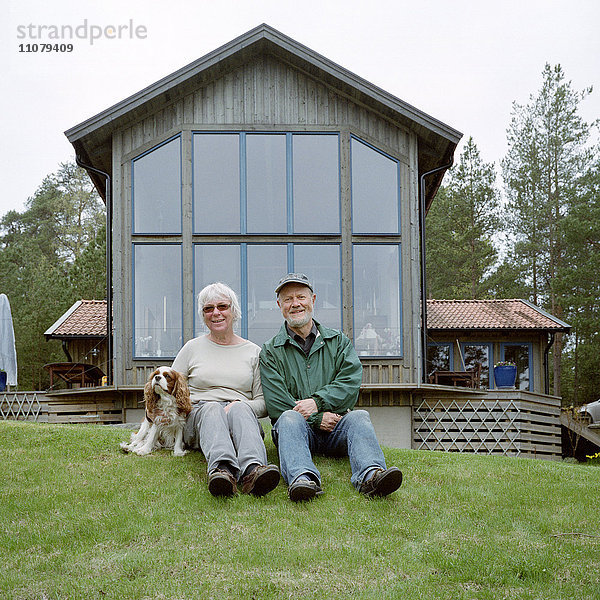 Älteres Paar im Gras sitzend  Porträt  lächelnd