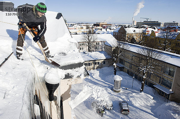 Mann entfernt Schnee vom Dach