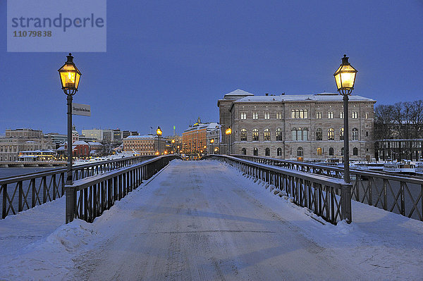 Straßenlaternen auf schneebedeckter Brücke  Gebäude im Hintergrund