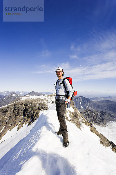 Mann steht auf dem Gipfel eines Berges