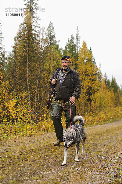 Mann geht mit Hund im Wald spazieren