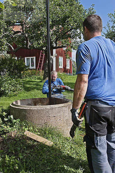 Handwerker arbeiten am Brunnen auf dem Bauernhof