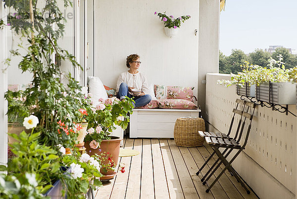 Frau entspannt auf Balkon