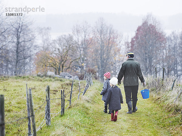 Großvater und Enkeltöchter gehen auf dem Fußweg
