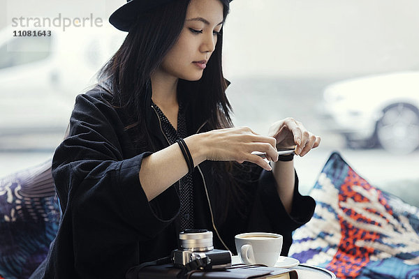 Junge Frau fotografiert Kaffee über Smartphone im Kreativbüro
